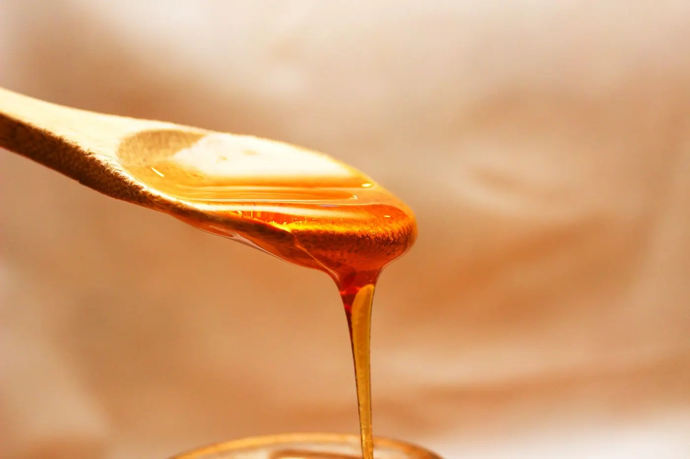 Густий бурштиновий сироп повільно стікає з дерев'яної ложки